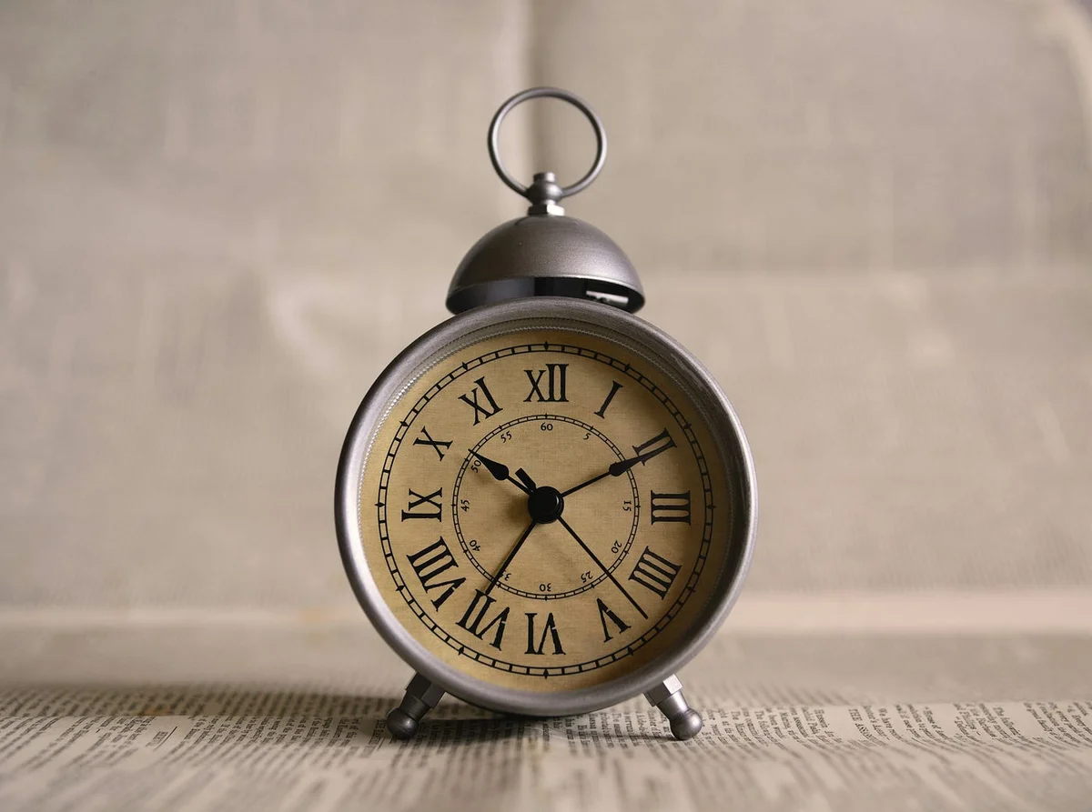 Vintage alarm clock standing on a newspaper